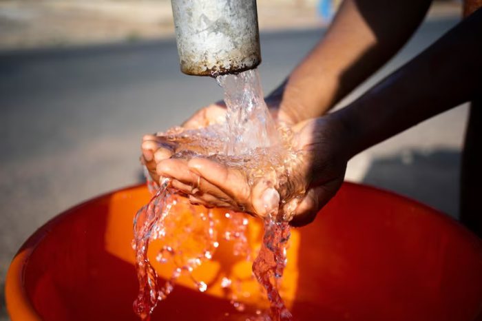 Hands collecting water flowing from a pipe